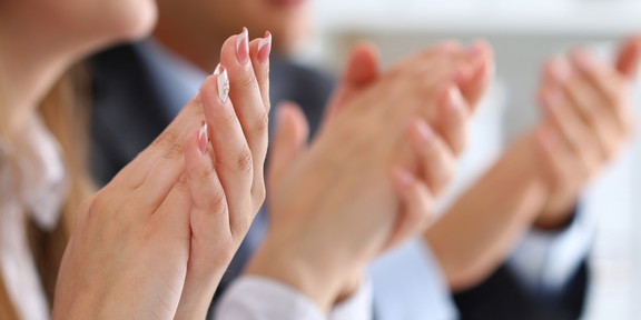 Several hands of women and men clap.