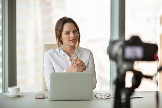 Video recording Woman sitting in front of her laptop and a video recorder